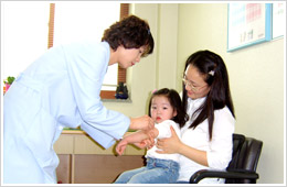 의사가 아기에게 주사를 놓아주고 솜으로 닦아주고 있다.